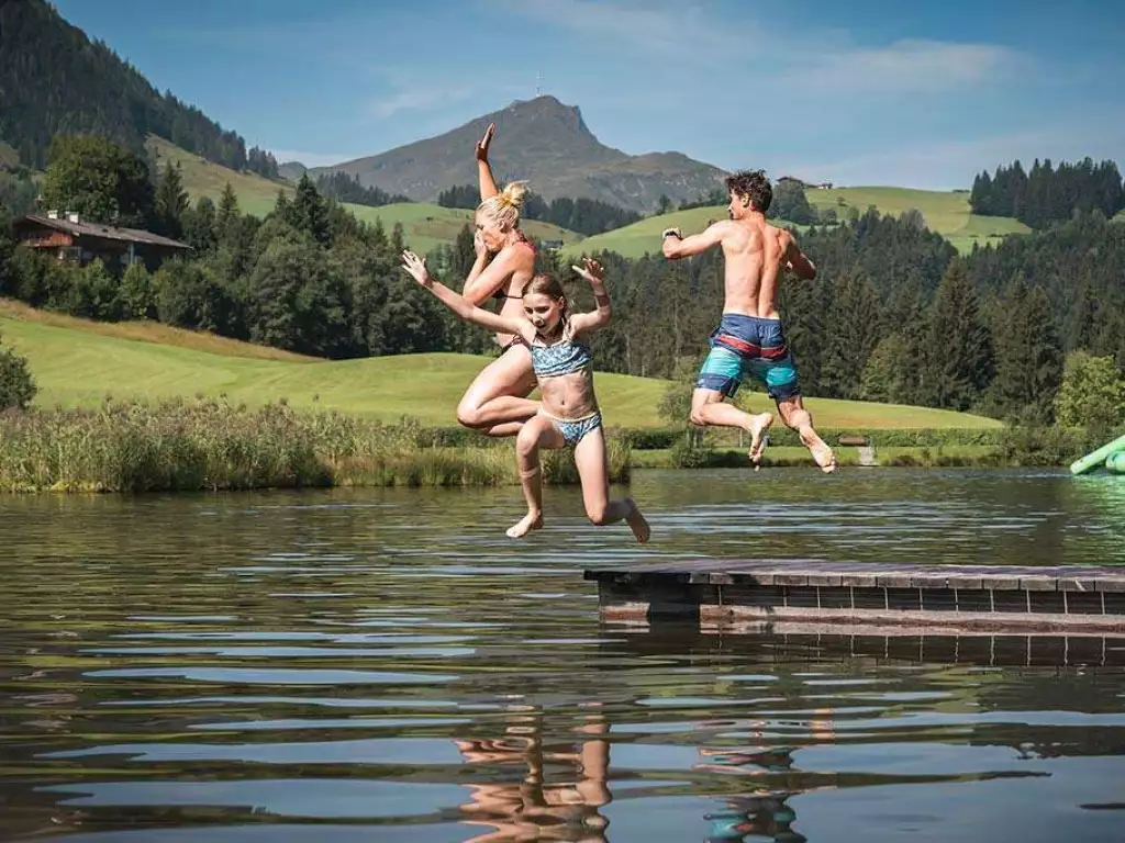 3 Kinder springen von einem Steeg in den See
